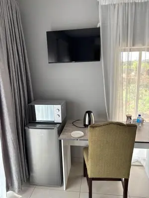 a desk with a computer and a chair next to a window at Glow Events &Guest House in Centurion