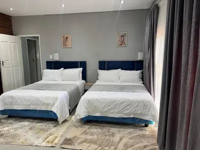 two beds sitting next to each other in a bedroom at Glow Events &Guest House in Centurion