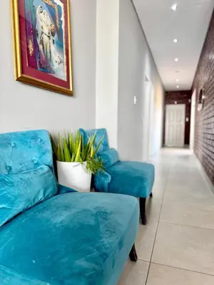 a living room with two blue chairs and a couch at Glow Events & Guest House in Centurion