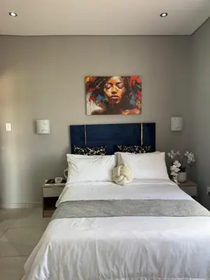 a bedroom with a large bed with a painting on the wall at Glowti Event & Guest House in Centurion