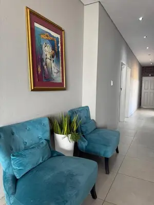 a living room with a blue couch and a chair at Glowti Events & Guest House in Centurion