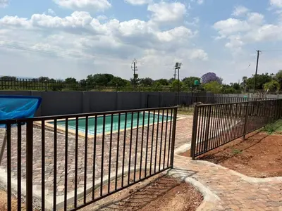 a metal fence around a swimming pool in a park at Glowti Events & Guest House in Centurion