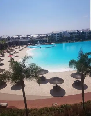 a large swimming pool with umbrellas and palm trees at The Corinthians in Pretoria