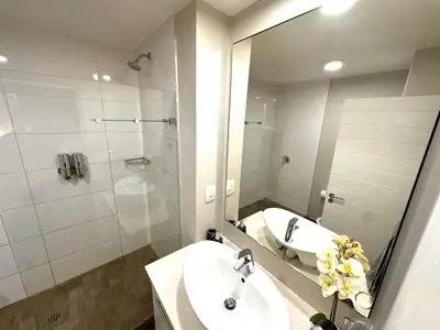 a bathroom with a sink and a shower with a mirror at Stay Menlyn - Luxe Apartment 617 in Pretoria