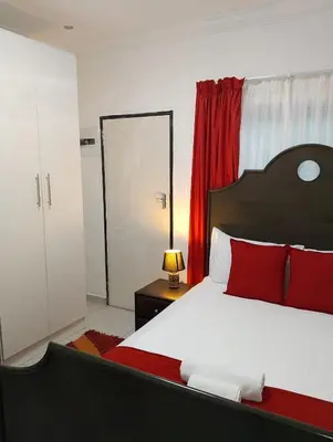 a bedroom with a bed with red pillows and a mirror at Millenium Manor in Centurion