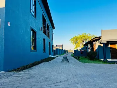 a cobblestone street next to a blue building at TLS Cottages in Buffelspruit
