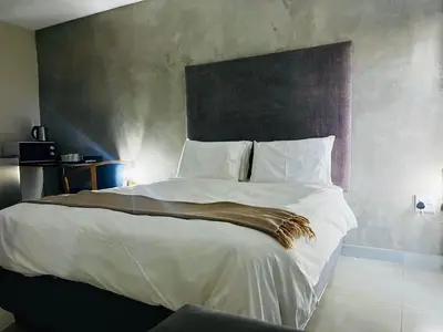 a bedroom with a large bed with white sheets at TLS Cottages