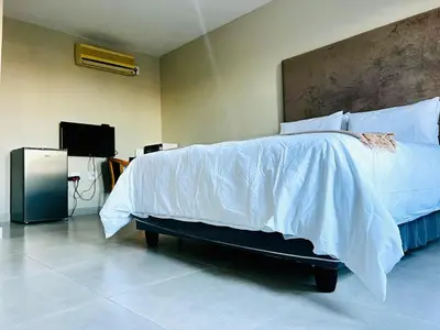 a bedroom with a bed with white sheets and a tv at TLS Cottages