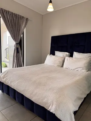 a large bed with a blue headboard in a bedroom at Staycation At Munyaka Estate in Midrand