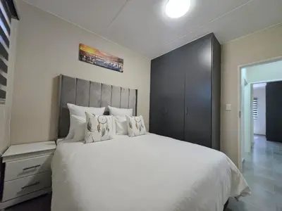 a bedroom with a large bed with white sheets and pillows at Nat's Villa in Midrand
