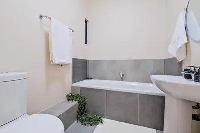 a bathroom with a toilet and a sink and a bath tub at Nat's Villa in Midrand