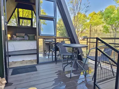 a room with a bed and a table on a deck at Braai & Bubbles - Modimolle in Modimolle
