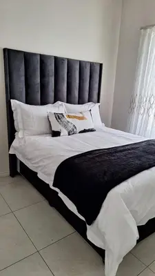 a large bed with a black headboard in a bedroom at Elegant & Timeless at 93 on new in Midrand