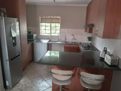 a kitchen with a sink and a counter with two stools at Nested at L&MX in Centurion