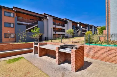 a brick bench in front of a building at Waterfall Smart Apartment in Midrand