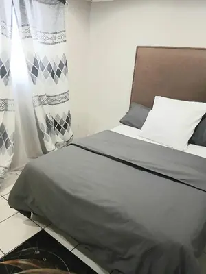 a bedroom with a bed with a gray comforter at Thonta house in Pretoria