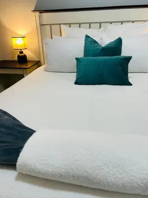 a white bed with blue pillows on it at Rugare Haven in Kempton Park
