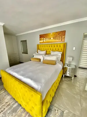 a large bed with a yellow headboard in a bedroom at ALIMU villa Mbombela in Nelspruit