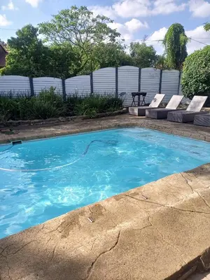 a swimming pool with blue water in a yard at The Tranquility Suite & Spa in Kempton Park