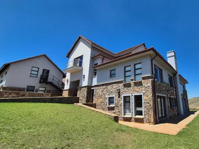 a large white house on a grassy field at Deluxe Suite at in Highland Gate Golf and Trout Estate 1135 in Dullstroom