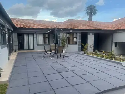 a patio with chairs and an umbrella in front of a house at MorningMist Boutique 27 Room 2 in Centurion