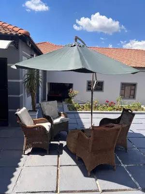 a group of chairs and an umbrella on a patio at MorningMist Boutique 27 Room 4 in Centurion