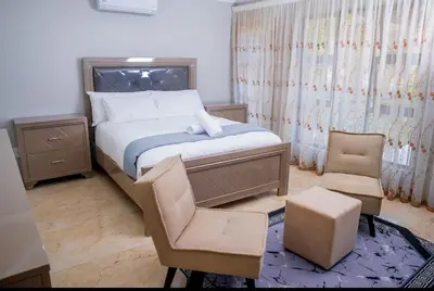 a small bedroom with a bed and a chair at Tindlovu GuestT House in Nelspruit