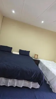 a bedroom with a large bed with blue sheets at ntaleguesthouse in Benoni