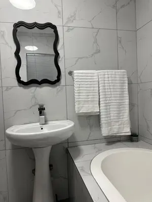 a white bathroom with a sink and a mirror at Pendleberry Grove 90 in Bela-Bela