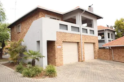 a brick house with two garage doors on a driveway at Nested at L&M in Centurion