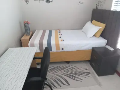 a small bedroom with a bed and a desk at Nested at L&M in Centurion
