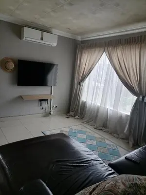 a living room with a couch and a large window at Imvumbu Guest House in Nelspruit