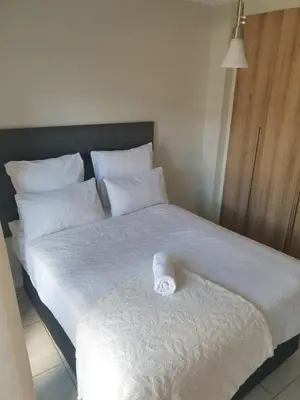 a white bed with a rolled up towel on it at Nompu b&b in Pretoria