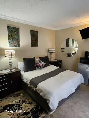 a bedroom with a large bed and a mirror at 16 Sleeper Holiday Home-Mansion in Hartbeespoort