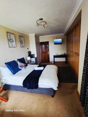 a bedroom with a large white bed with blue pillows at 16 Sleeper Holiday Home-Mansion in Hartbeespoort