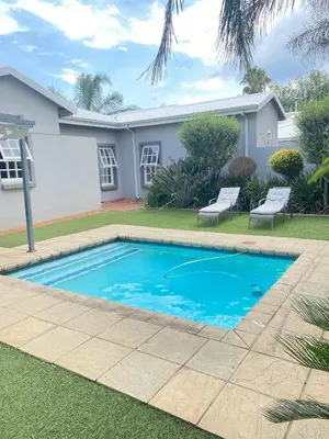 a swimming pool in front of a house at Asanda Retreat in Kempton Park
