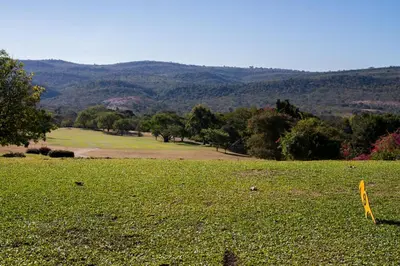 a grassy field with trees and mountains in the background at Kruger Park Lodge Unit No 219 in Hazyview