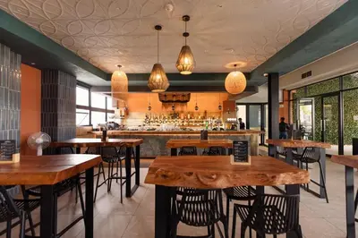 a restaurant with wooden tables and chairs and a bar at The Dream Escape At The Blyde - One Bedroom Apartment in Pretoria
