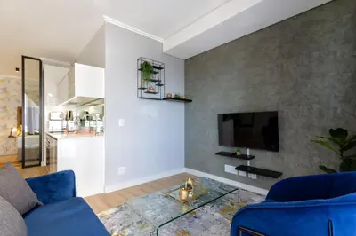 a living room with a blue couch and a tv at #AlimamaSpaces The Ace's Ellipse in Midrand