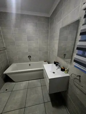 a bathroom with a white tub and a sink at The Blyde Estate Apartments in Pretoria