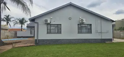 a white house with two windows and a yard at Good night guest house in Polokwane