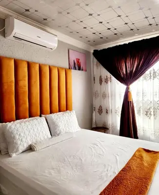a bedroom with a white bed with an orange wall at Kiba guest house in Marble Hall