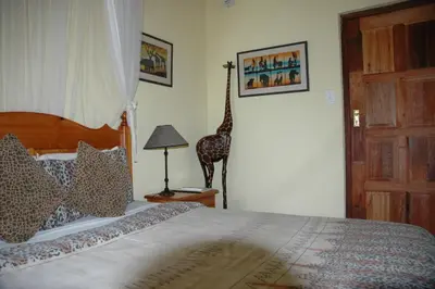a bedroom with a bed with a giraffe on the wall at Trees Too Guest Lodge in Komatipoort