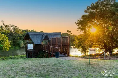 a wooden building with the sun setting in the background at Kruger Park Lodge Unit No 252 with private pool in Hazyview