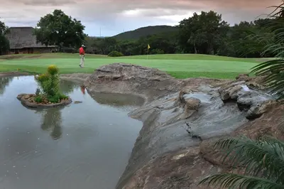 a man standing on a golf course next to a pond at Kruger Park Lodge Unit No. 608B in Hazyview