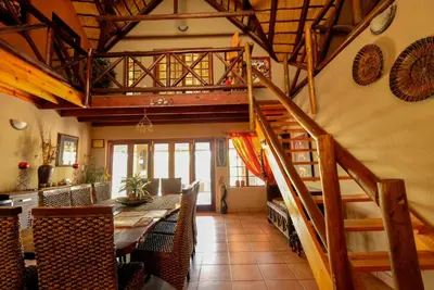 a dining room with a staircase and a dining table at Lovely holiday home bordering Kruger National Park in Marloth Park