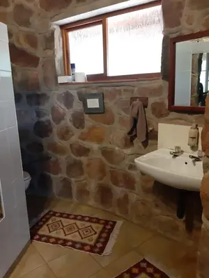 a stone bathroom with a sink and a mirror at Cross Pollination Chalets & Camping in Vaalwater