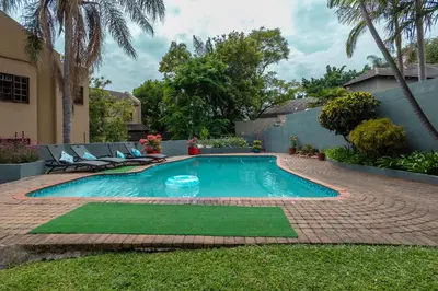 a swimming pool in a yard with chairs and trees at Rozelee Rest in Nelspruit