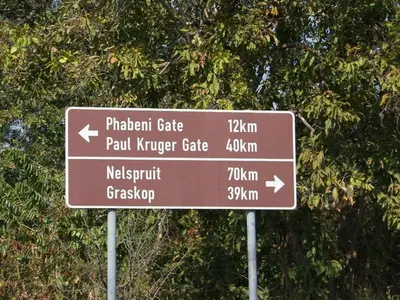 a brown street sign in front of a tree at Kruger Park Lodge - IKZ2 - 3 Bedroom Chalet in Hazyview