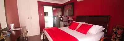 a red bedroom with a bed with red pillows at Casa de Ross in Pretoria